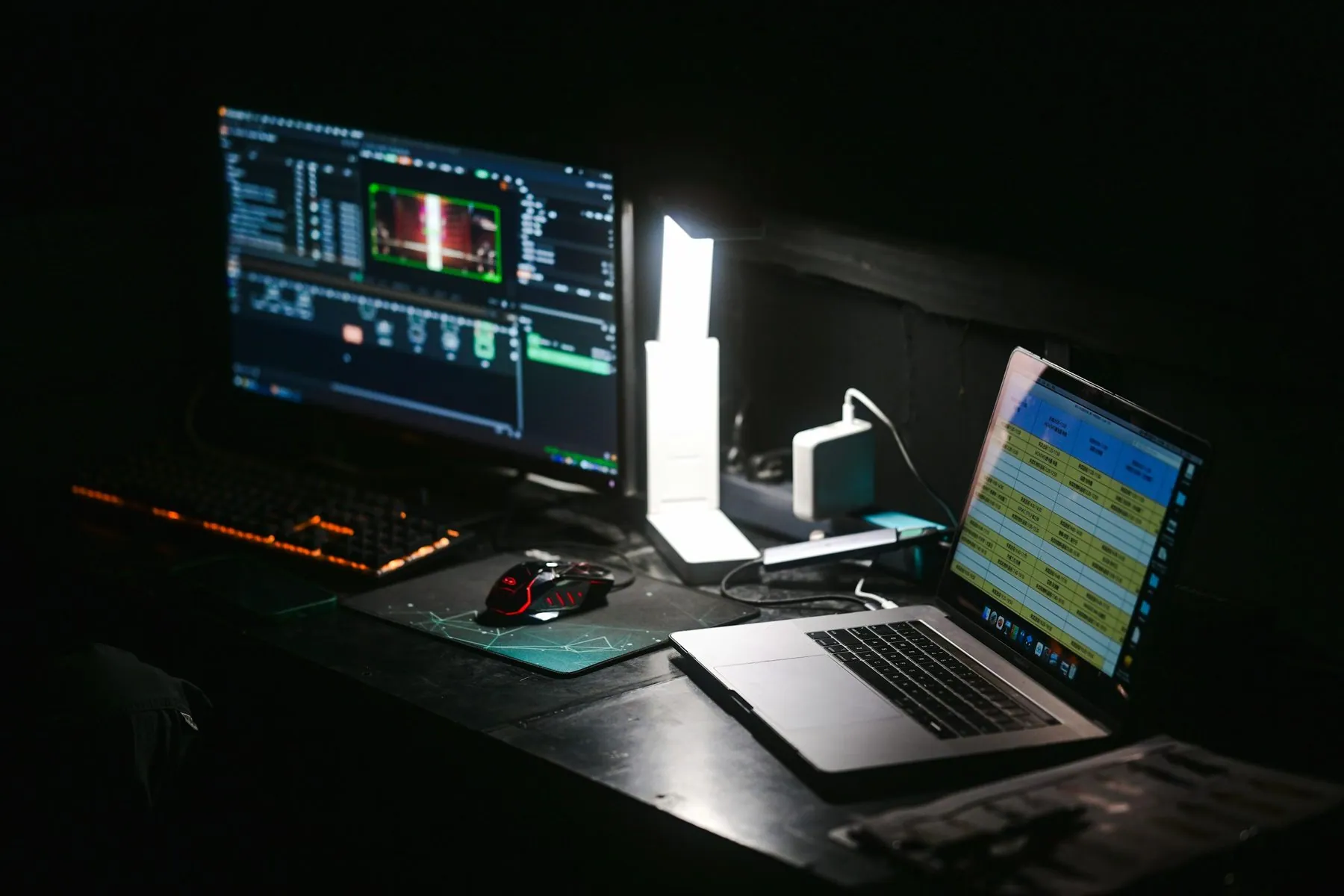 A laptop and a computer monitor on a dark desk in a workspace