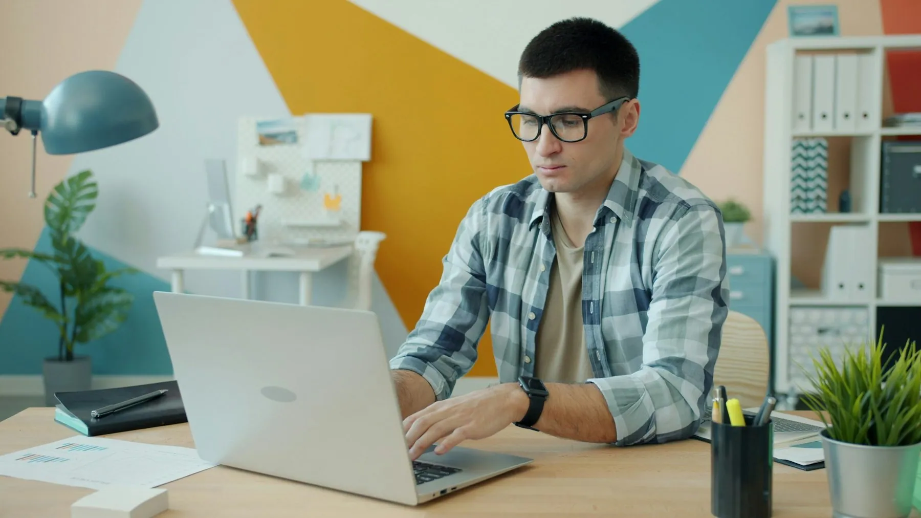 Office employee serious young man is working with computer then turning off laptop finishing work sitting at desk in roo