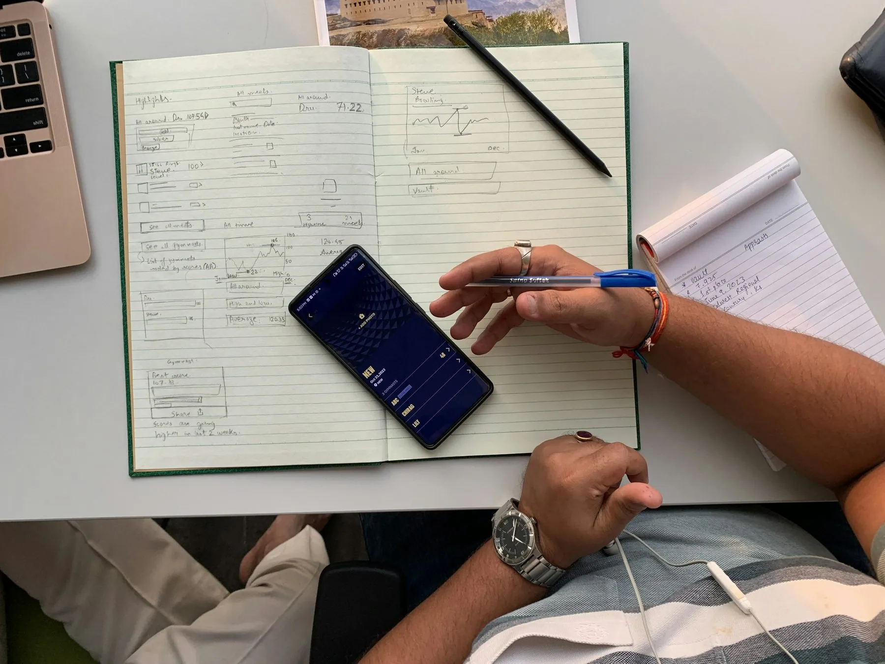 a person sitting at a desk with a notebook and a cell phone