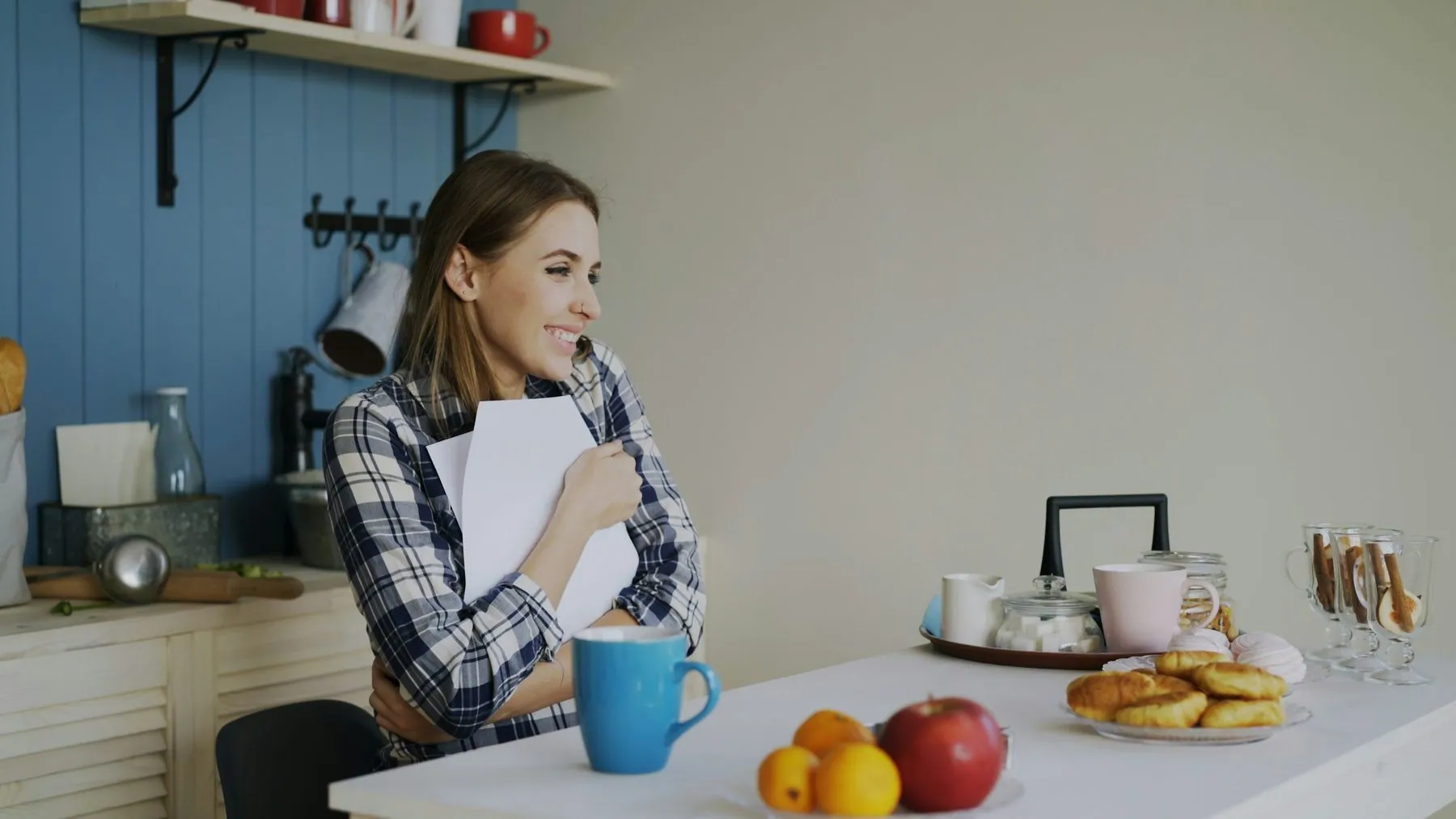 Young happy woman surprised to recieve good news reading letter in the kitchen while have breakfast at home
