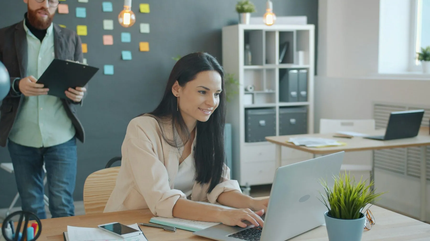 Businessman and businesswoman discussing business document in creative office talking looking at paper, woman is using l