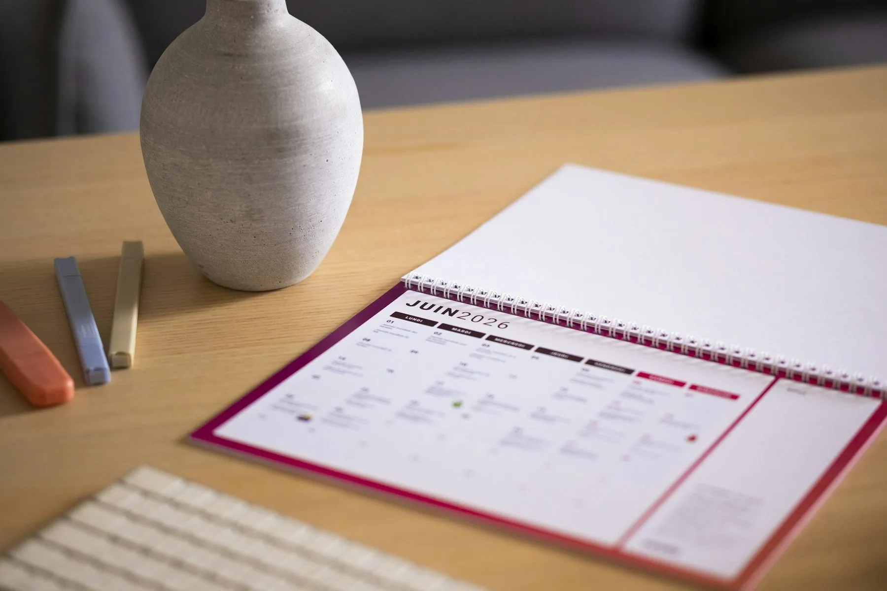 A calendar and vase sit on a wooden desk