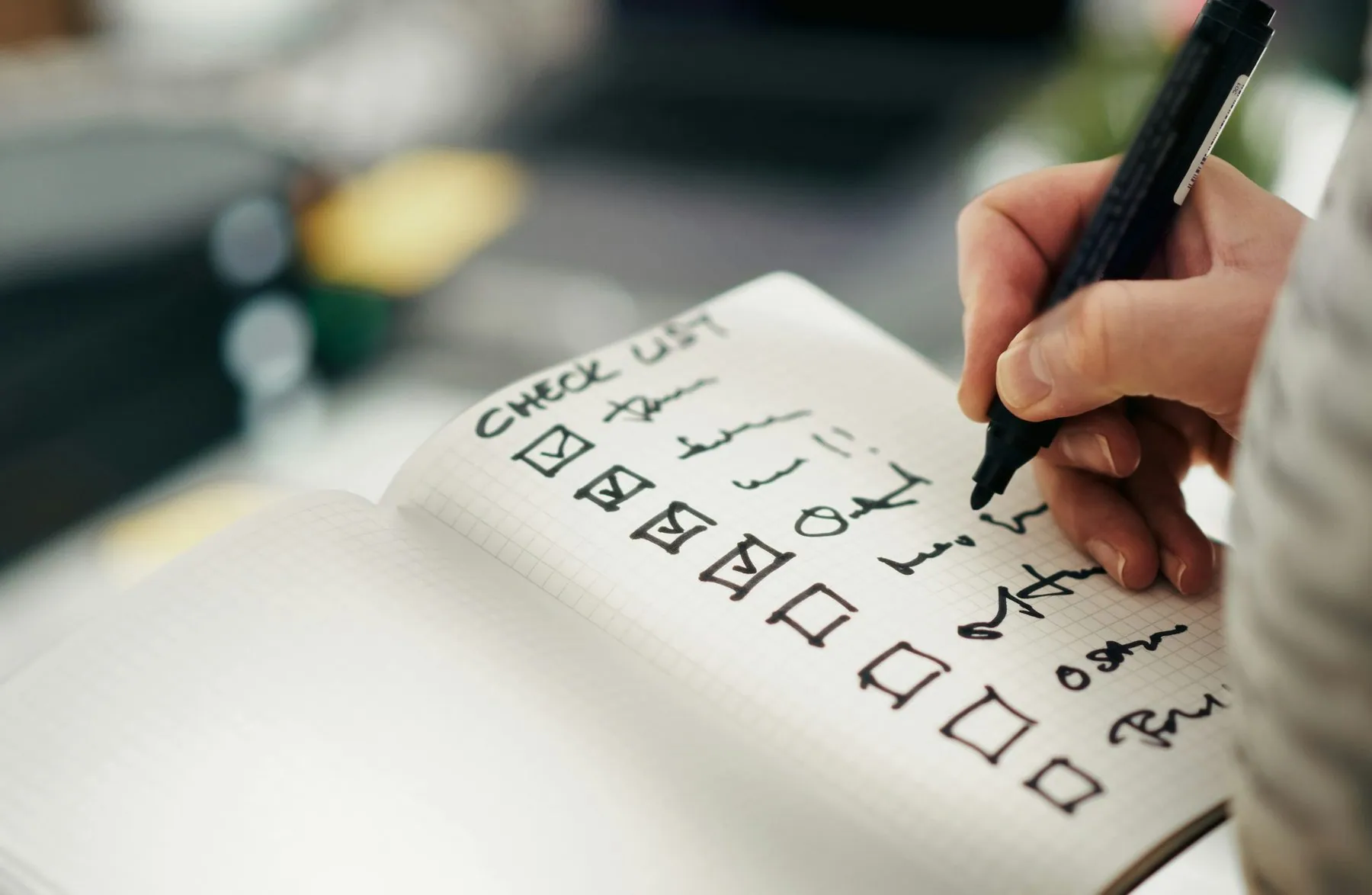 Checklist notebook task progress accuracy. Close-up hand holding pen while marking completed tasks grid notebook. Symbol