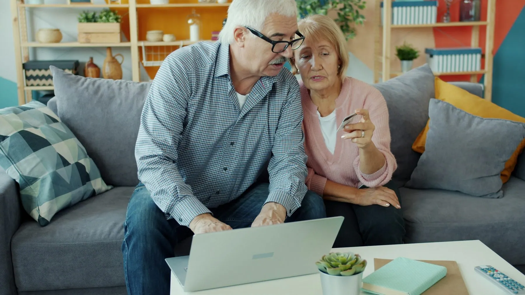 senior man and woman making electronic online payment with bank card using laptop at home. Money, retirement and shoppin