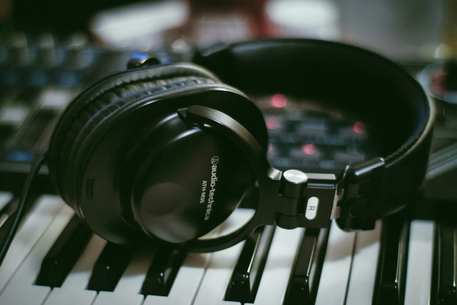 Black headphones resting on a white and black piano keyboard in a studio