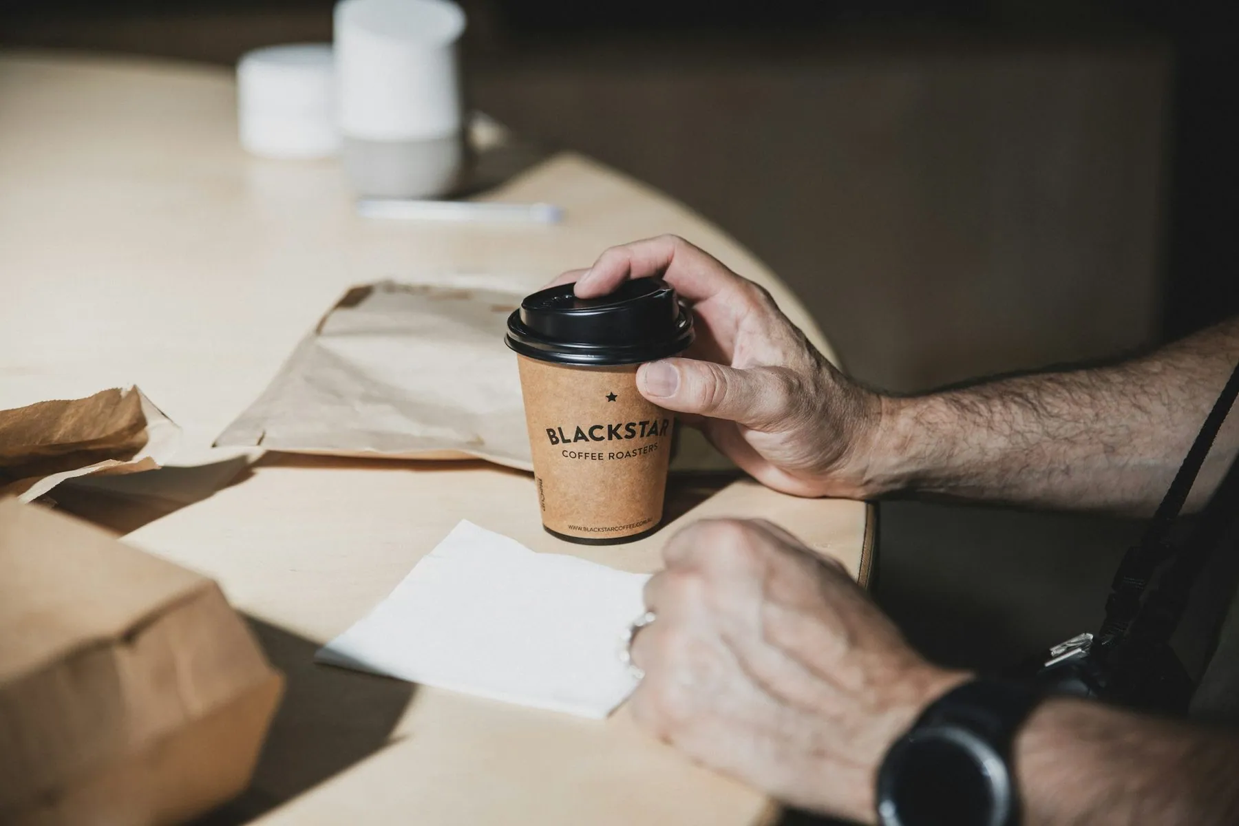 person holding brown and black coffee cup