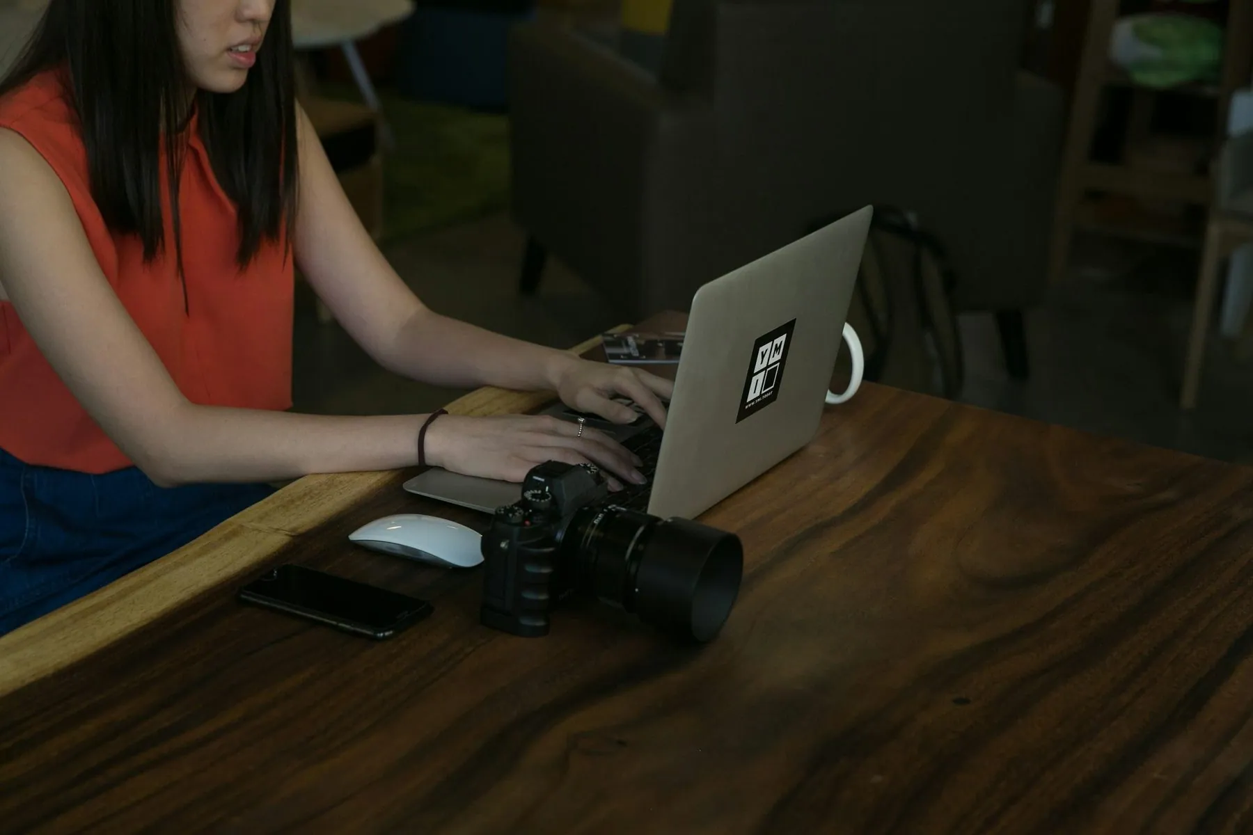 Creative professional woman typing on laptop with camera equipment on table beside her. Freelance work photography for r