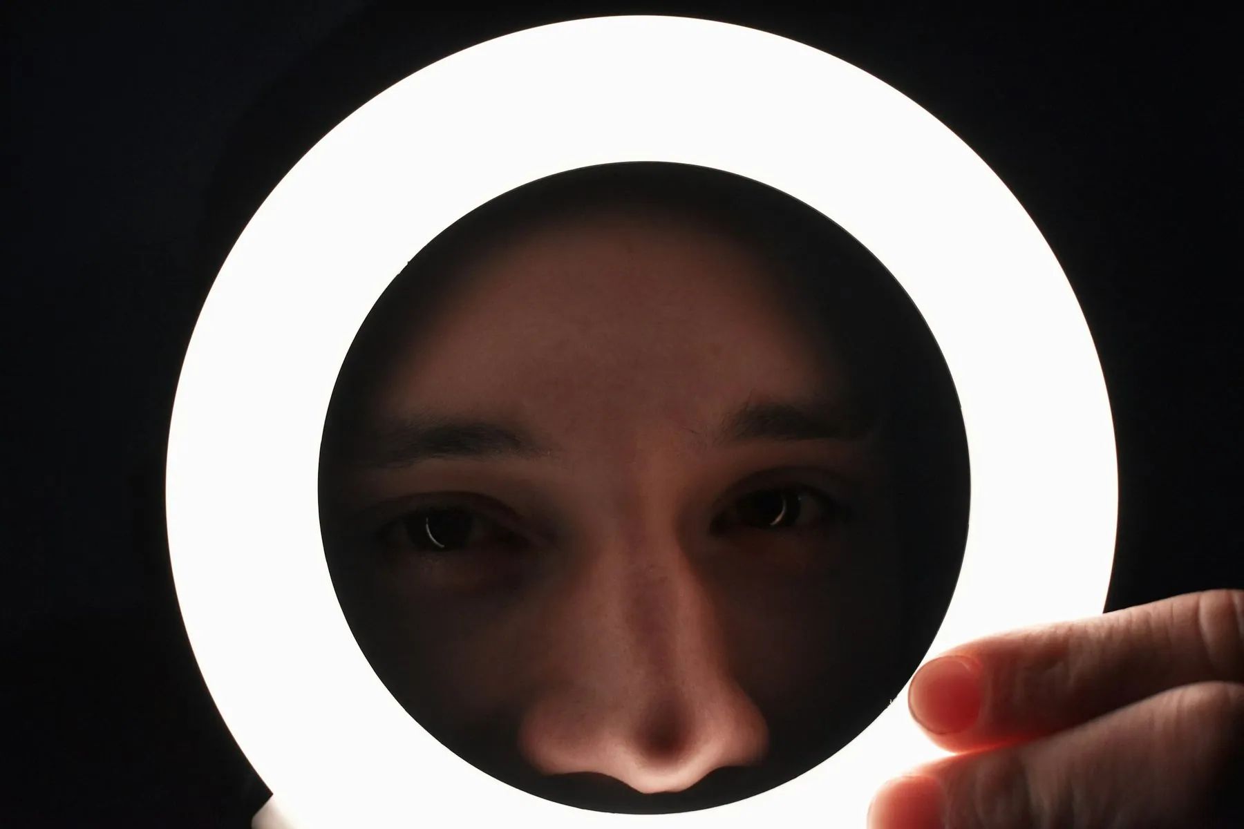 a person holding a circular light up to their face