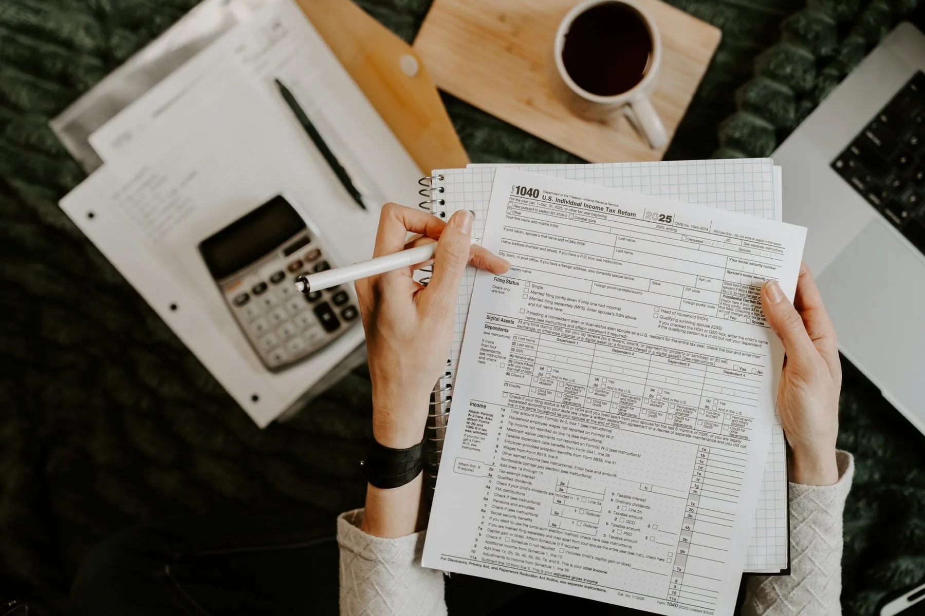 Person reviewing documents with calculator and laptop
