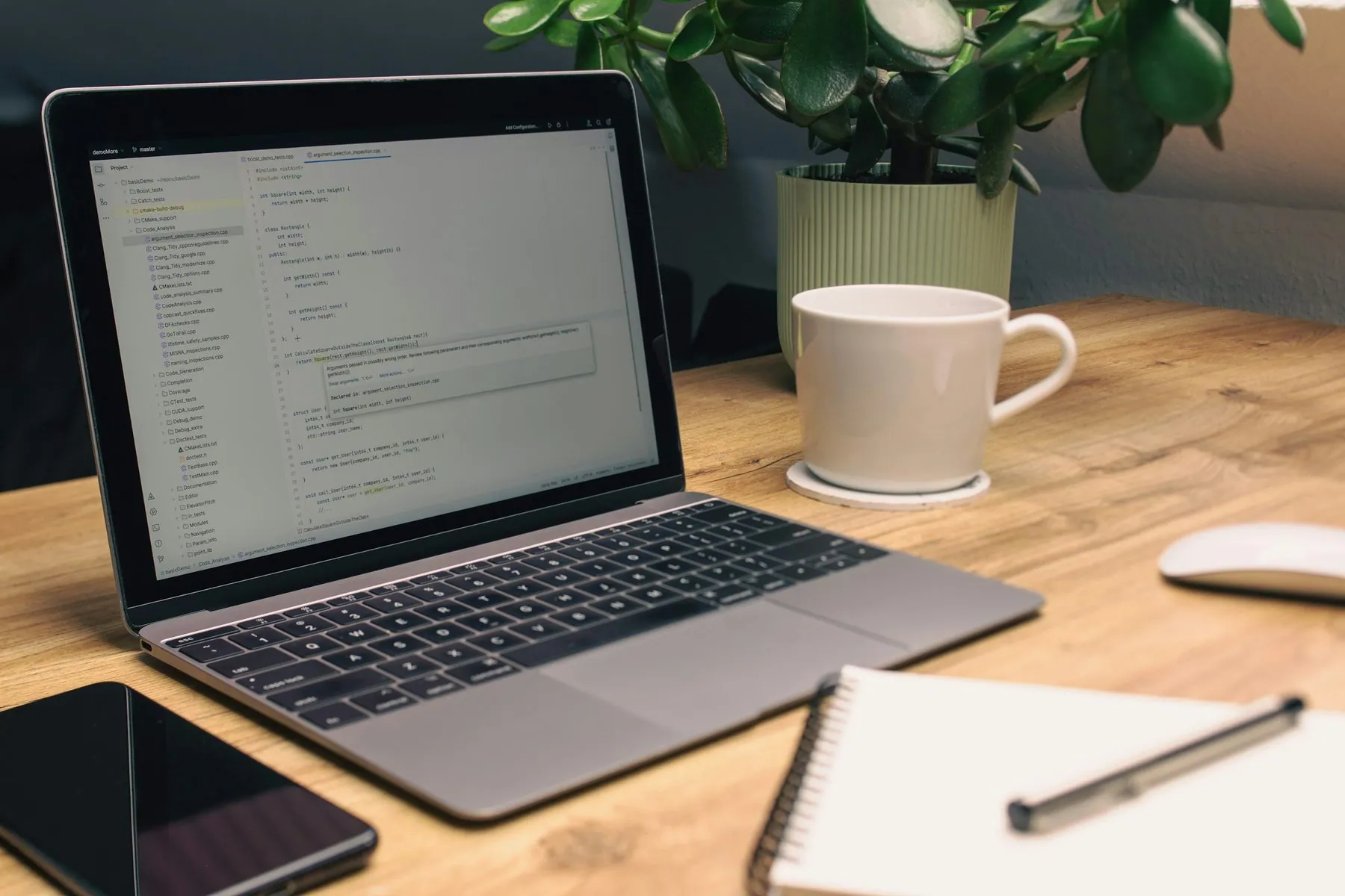 Laptop, notebook, phone, and mug on desk