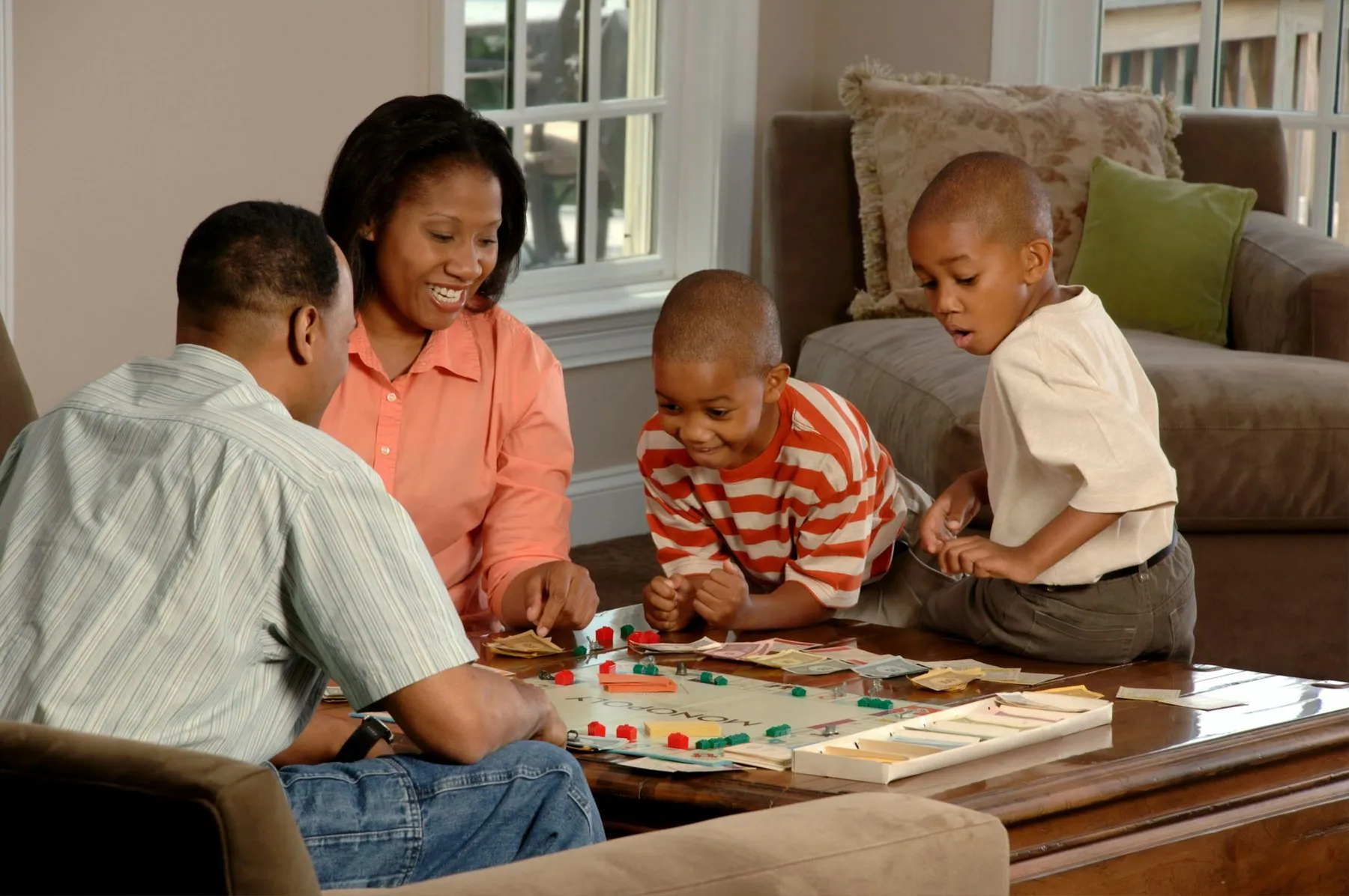 Family Playing Board Game. An African-American family (adult male and female and two male children) sit around a coffee 