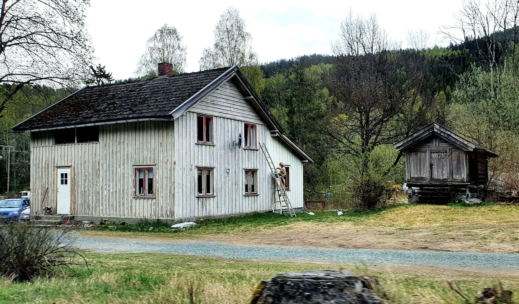 A weathered wooden house with a small shed