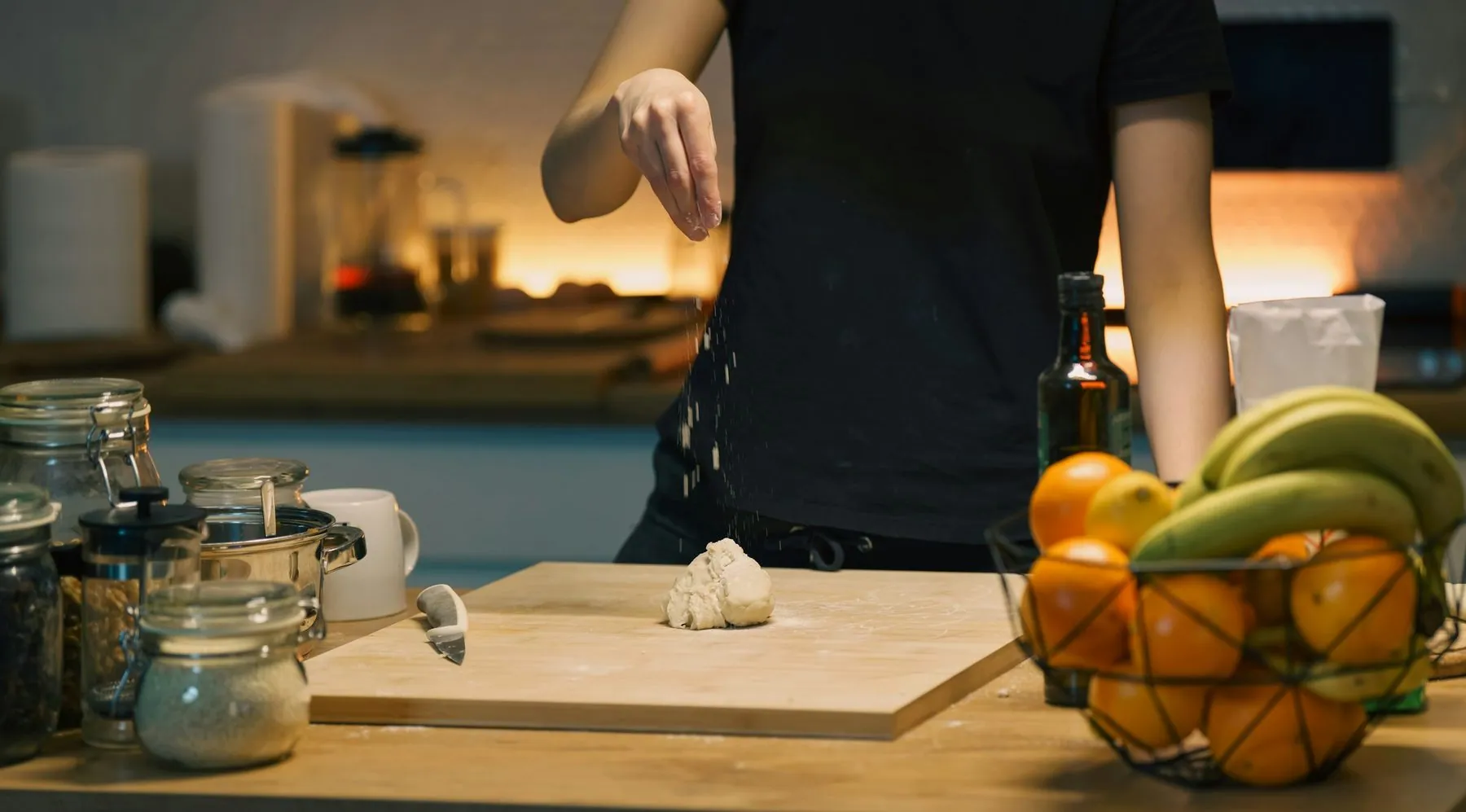 Home kitchen dough preparation flour falling scene. Unrecognizable person seasoning fresh dough on wooden board, cozy in