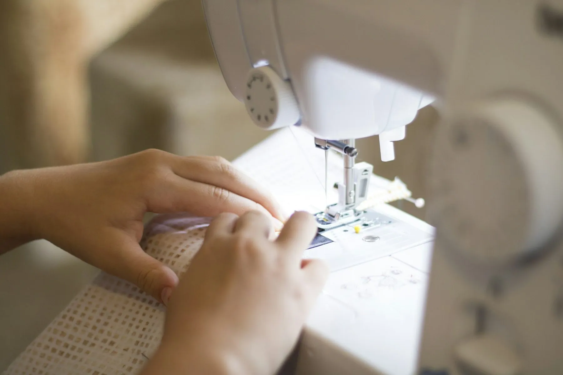 A child's hands guides fabric on a Brother sewing machine.